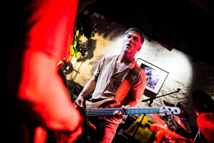 Een muzikant speelt gitaar op het podium met levendige verlichting.