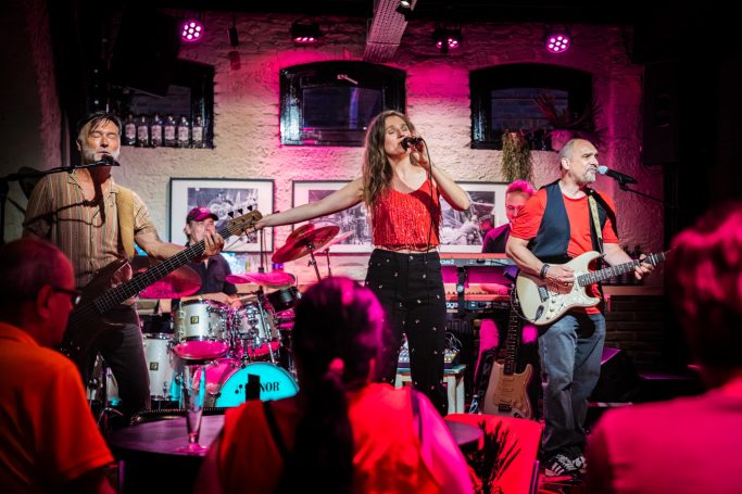 Een band met drie muzikanten speelt live muziek in een sfeervolle club.