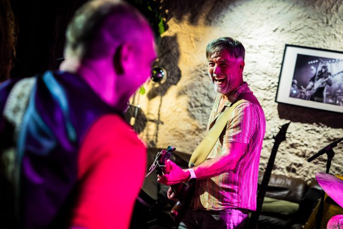 Twee muzikanten spelen samen op een podium in een sfeervolle setting.