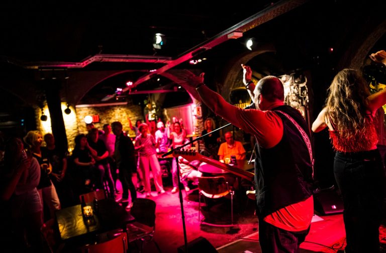 Een muzikant op het podium met een enthousiaste menigte in een sfeervolle locatie.